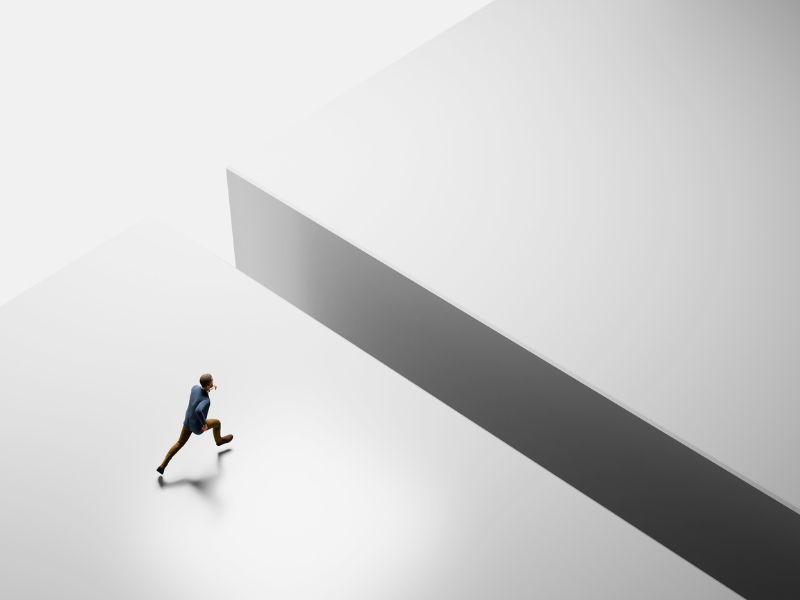 A man in a suit running on a white surface, unaware of a dark gap in front of him that he is about to step into.